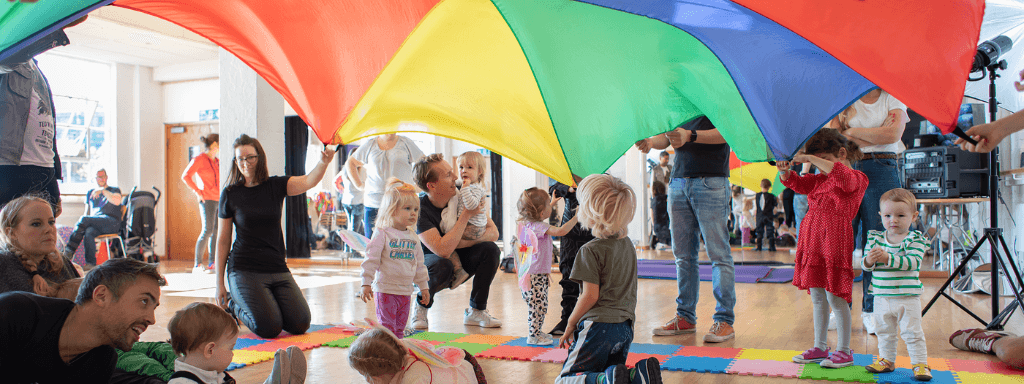 Budget 2023 -image shows a baby class for 0-5 year olds, with toddlers playing parachute games with their parents