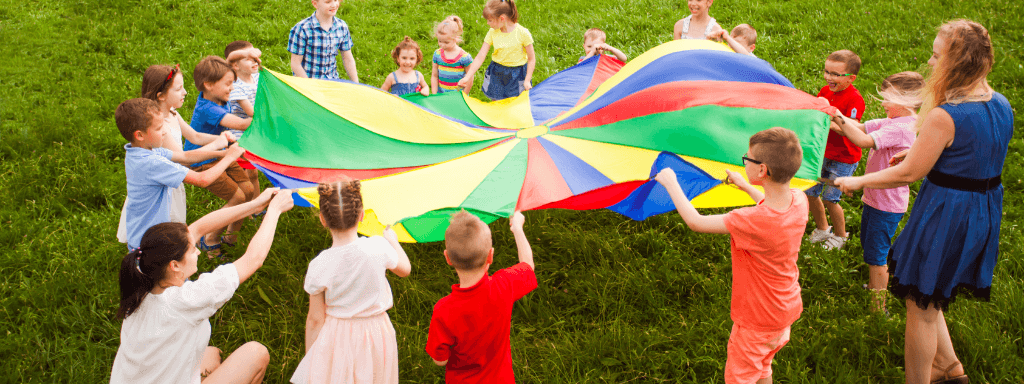 Your business and the summer holidays: image shows a group of kids of mixed ages playing parachute games